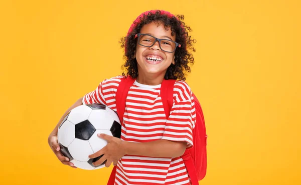 陽気で面白いアフリカ系アメリカ人の少年 黄色い背景に対する研究の後にサッカーボールを運ぶカジュアルな服 — ストック写真