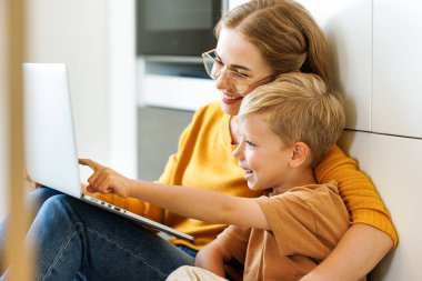 Mutlu bir aile çocuğu ve genç bir annesi var. Bilgisayar kullanıyor ve evde dizüstü bilgisayardan komik videolar izliyorlar. 