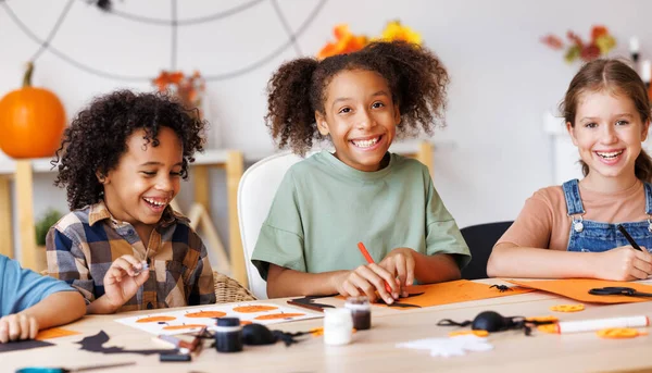 ハロウィーンの家の装飾を一緒に作る子供の多国籍グループ 子供はカボチャを絵画し 紙の切断を作る ストックフォト