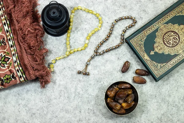 stock image lantern and Holy Quran with Arabic calligraphy meaning of Al Quran and prayer mat , rosary muslim and dates fruits