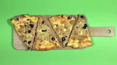 Yakın plan eller peynirli, domatesli ve zeytinli ton balıklı pizza tutuyor.