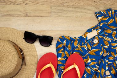 Elveda ya da merhaba yaz konsepti, güneş gözlüğü ve şapka ve terlik ve ahşap masa üzerindeki maksi elbise.