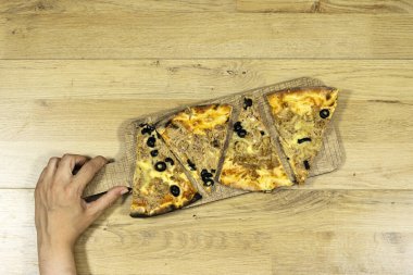 Ton balıklı pizza yiyen bir kadın.