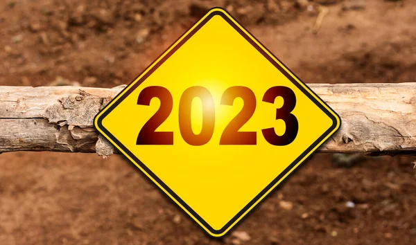 Road sign indicating happy new year 2023 on tree trunk