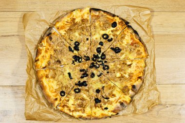 Peynirli, domatesli ve ahşap masada zeytinli ton balıklı pizza. 