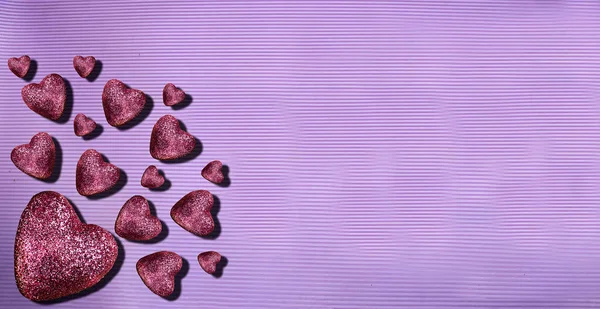 purple glitter hearts on purple background. Heart of glitter grains glitter makeup. background, abstract