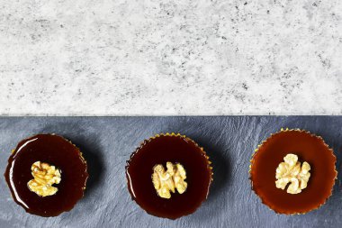 Ev yapımı lezzetli küçük cevizli karamel cheesecake siyah tabakta.