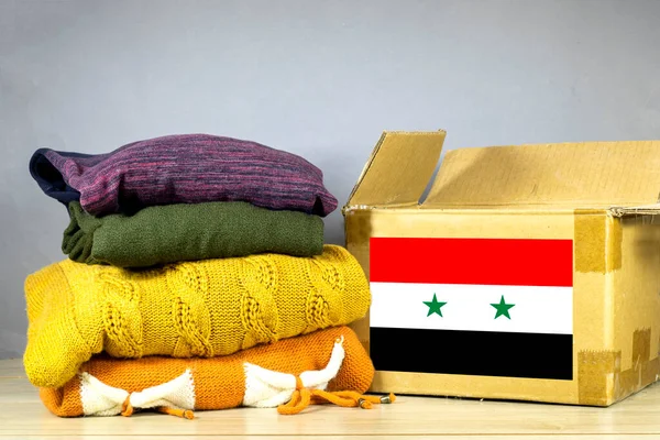 carton box with used clothes for donation and Syria flag Earthquake, catastrophe volunteering