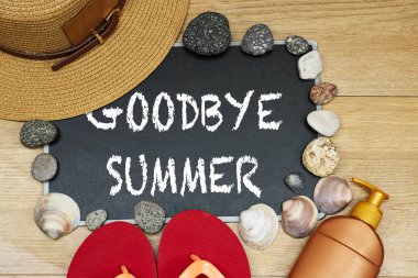 goodbye or hello summer concept, sun cream and slipper with chalkboard and stones. seashell on wood table