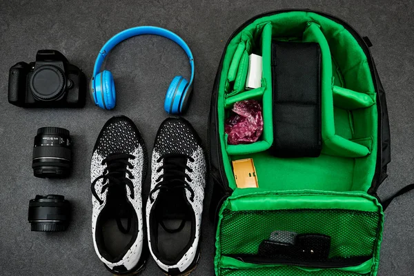 Professional Photography Gear : camera and lenses, blue wireless headphone and black shoes on grunge gray background