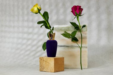 Üç boyutlu ahşap küpün üzerinde gül çiçekleri olan pelüş mor parfümlü mermer podyum ya da taş güzellik. Ürün tanıtımı Güzellik kozmetik vitrini