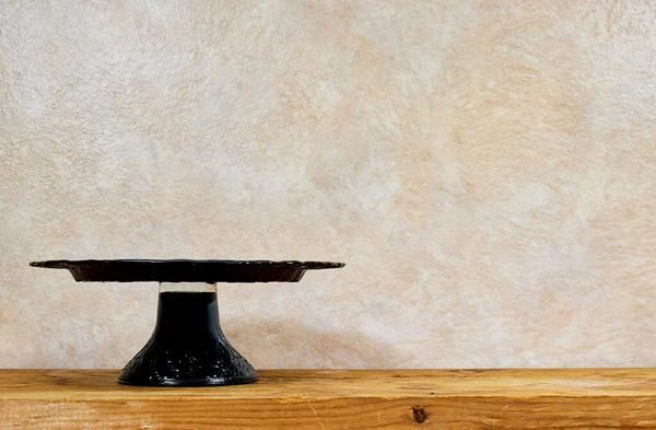 empty black cake stand on wooden table near grunge background