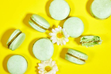 Sarı arka planda papatya çiçekli Fransız fıstıklı badem kurabiyesi.