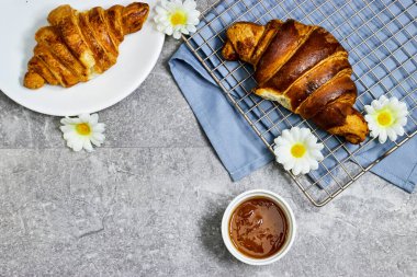 Kahvaltıda portakal reçelli taze kruvasan ve papatya çiçeği. Gri beton bir masada Avrupalı kahvaltısı. Üst Manzara. Düz yatıyordu