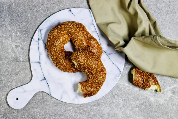 Geleneksel Türk kahvaltısı mermer kesim tahtasının üzerinde simit simit var. 