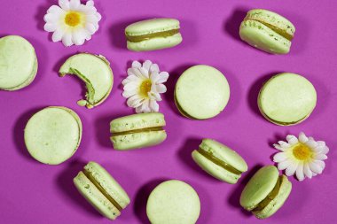 Mor arka planda papatya çiçekli Fransız fıstıklı badem kurabiyesi.