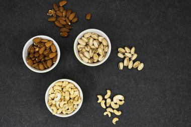 nuts (almonds, pistachio, cashews) in bowls on grunge background 