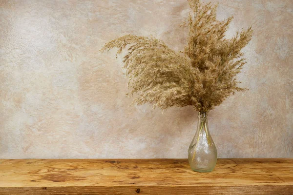 stock image Vase of golden reeds on wood board  with copy space