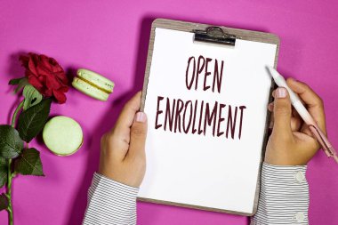 closeup woman holding a yellow card with open enrollment