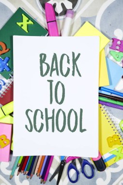 Okul konseptine geri dönelim - kalemler ve defterler ve yapışkan notlar ve raptiyelerle, keçeli kalem arka planda