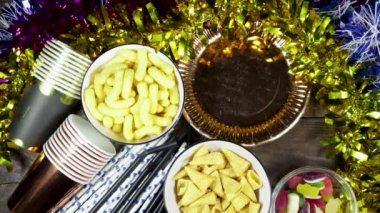 Doğum günü ya da Noel, yeni yıl partisi konsepti, kartla kutlanan kağıt tabak metin ve tek kullanımlık bardak, pipet ve renkli farklı cips ve şekerlerle ahşap masa.