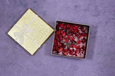 Açık parlayan altın kutu mor grunge arka planda kurumuş çiçekler içerir.