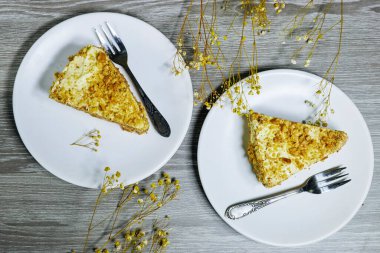 Cevizli kek ya da kremalı Kiev pastası ve gri ahşap arka planda beyaz tabakta servis edilen vanilyalı tereyağı.