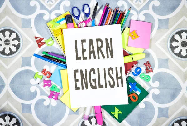 Learn english concept - pencils and notebooks and sticky note and with pins, felt pen on tile background