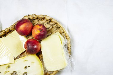 Bir tepsi şeftali, gruyere ve gouda peyniri, arka planda izole edilmiş peynir.