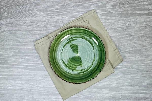 empty round green plate on tablecloth for food on wood table. Empty dish on napkin with space for your design