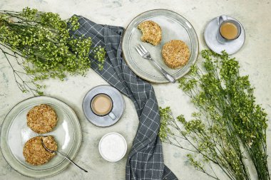 Siyah tabakta ev yapımı vanilyalı kek, kahve fincanı ve çigila çiçekleri.