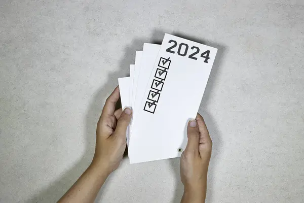 hands holding a card withNew year goals 2024. 2024 goals list.Resolutions, plan, goals, action, checklist, idea concept. New Year 2024 template