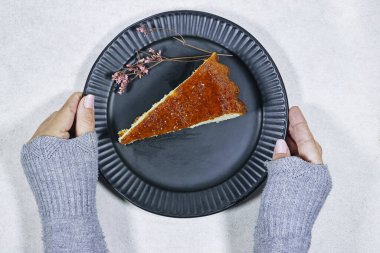 El yapımı tatlı, kayısı reçelli ve Gypila çiçeğiyle süslenmiş romlu bebek tabağı tutan kadın.