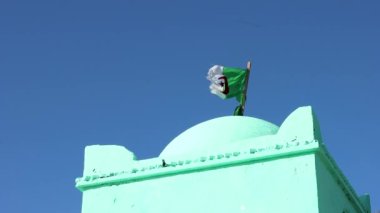 Cezayir ulusal bayrak kumaşı eski tarihi anıt mezarın üzerinde gökyüzünde sallanıyor 