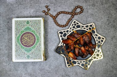 Arapça kaligrafi Kuran çevirisi ile kapatılmış müslüman kitabı: Müslümanların kutsal kitabı ve hurma meyveleri, tasbih. iftar ramazanı kavramı