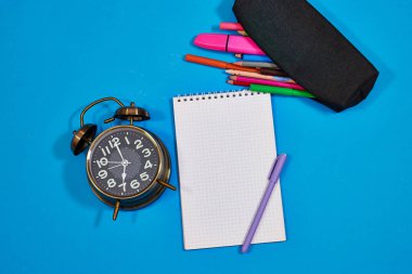 Okul konseptine geri dönme zamanı. Alarm saati, kalemler, defterler ve keçeli kalemler.