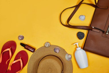 Elveda ya da merhaba yaz konsepti, güneş gözlüklü kahverengi kumsal çantası ve şapka ve terlik, krem rengi güneş ve yağ şişesi ve taşlar, deniz kabuğu