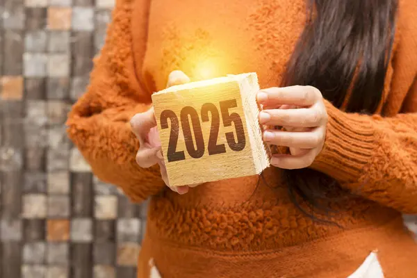 2025 sayılı ahşap küpü elinde tutan yakın plan kadın, 2025 yılbaşı tebrik kartı şablonu.