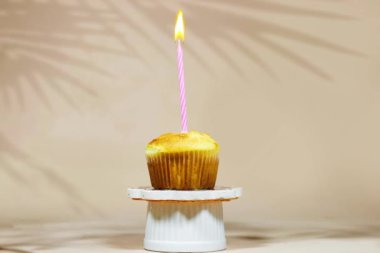 Kürsüde doğum günü pastası bej arka planda bir doğum günü pastası mumu