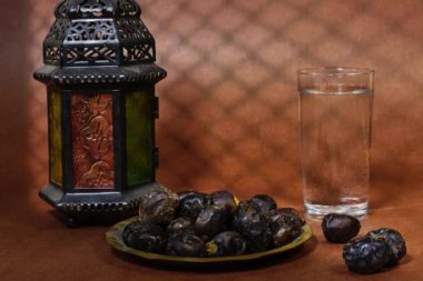 Ramazan iftar kavramı, Ajwa cam su ve fenerle meyveler ve bükülmüş pencere gölgesi olan bir kadın.