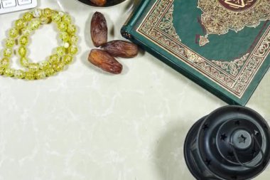 Bayram konsepti. Arapça kaligrafi Kuran ile fener ve müslüman kitabı - çeviri: dünyanın dört bir yanındaki Müslümanların asil kitabı ve meyveler, tespih taşları 