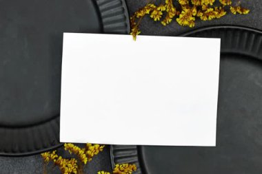 Düğün davetiyesi modeli siyah seramik tabağın üzerinde gri arka planda gypthe ile birlikte. Boş kart maketi