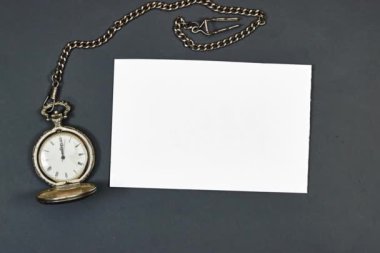 Düğün davetiyesi modeli ve gri arka planda antik gümüş cep saati. Boş kart maketi