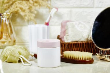 Düzenli bir banyo tezgahı, banyo malzemeleri, mermer arka planda krema kavanozu.