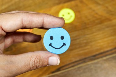 Emoticon 'un gülümseyen yüzünü tutan kadın. Müşteri hizmetleri memnuniyet konsepti