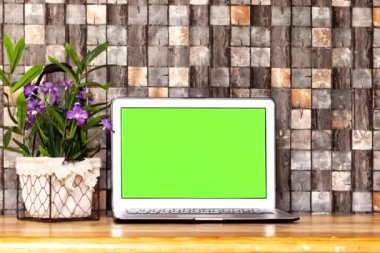 Masaüstünde çiçek sepetli yeşil ekran laptop 