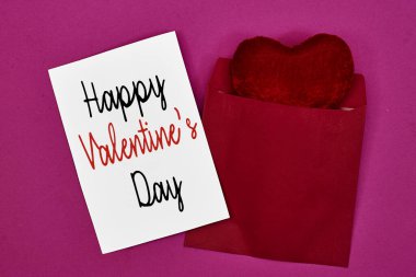 Sevgililer günü davetiye taslağın ve pembe arka planda kırmızı kalp oyuncağı olan beyaz zarfın kutlu olsun. Boş kart maketi