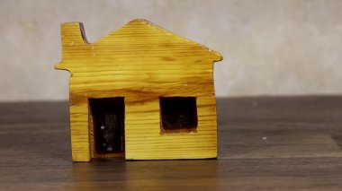 Beyaz dantele sarılı kırmızı bir kalp dekoru eşliğinde ahşap minyatür bir ev. Evi ve sevgiyi sembolize ediyor. Sıcak ve duygusal bir ruh hali yaratıyor.