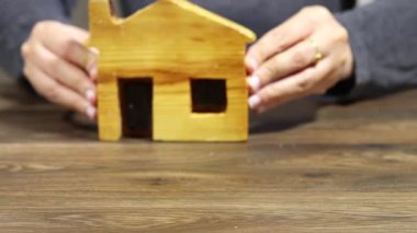 Ahşap masada Tahta Ev Modeli Tutan Eller