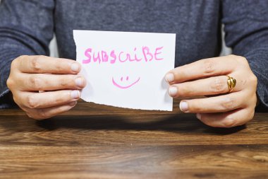 Abone metni ile bir kağıt notu tutan el.